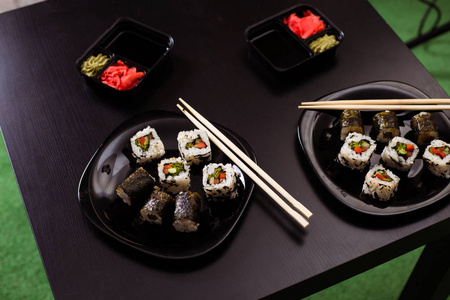 供应一盘日本料理。卷或寿司放在桌子上的黑色盘子里。