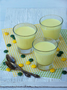 黄色甜点公费旅游从牛奶和皱胃酶提取姜黄在浅色背景上的眼镜。由甜奶酪制成的果冻似的布丁。健康的食物。文本的空间