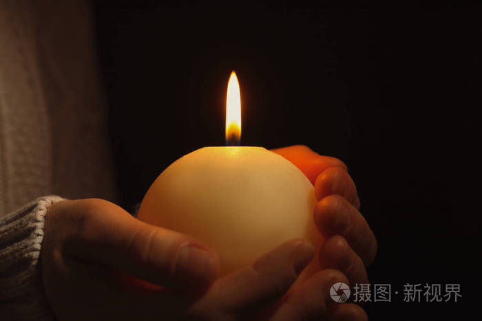 年轻的人手持燃烧的蜡烛在黑暗中, 特写