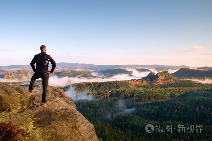 徒步旅行者站在悬崖上的砂岩帝国公园和注视着雾气很重,有雾的早晨谷