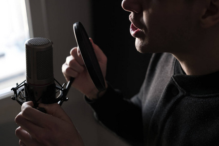 一个近距离的麦克风唱歌的年轻男人站在嘴唇照片