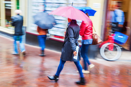 妇女带着伞走在多雨的城市