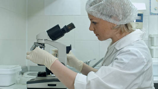 研究员戴上手套, 在实验室里使用显微镜