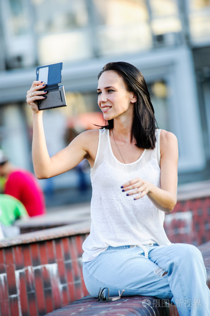 杨和美丽的现代商业女人姿势户外与智能手机