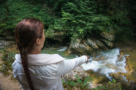 年轻女孩徒步者站立在山峡谷之上与河