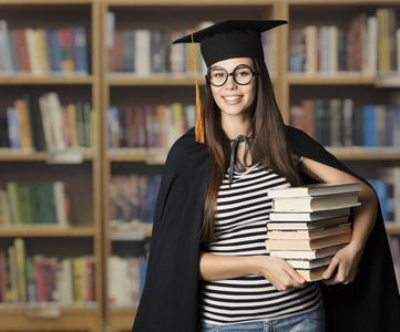学生在毕业帽子捧着教育书，眼镜，大学图书馆的少爷女人