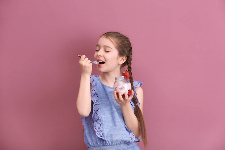 可爱的女孩吃可口的酸奶在颜色背景