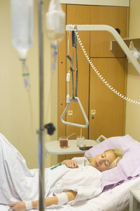 卧病在床的女病人，在医院照顾手术后恢复