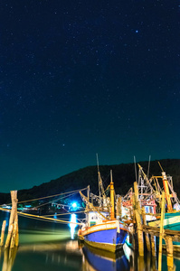渔船停泊在港口在满天星斗的天空
