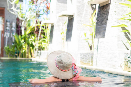 年轻女子在泳装在游泳池里华丽度假村 豪华别墅 热带巴厘岛，印度尼西亚