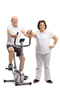 成熟的人在固定的自行车锻炼与一个成熟的女人靠在白色背景上孤立