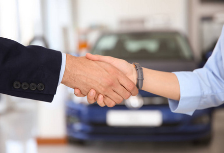 年轻推销员在汽车经销店与客户握手