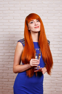 年轻漂亮的红头发的女人晚礼服喝 champagn