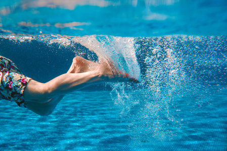 夏季男子腿在游泳池水下游泳