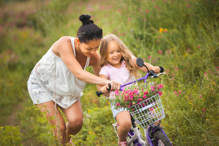 年轻漂亮的妈妈教她的小女儿骑双