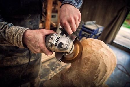一个经验丰富的木匠在工作服装和小付多少营业税业主在木工车间工作, 处理板上的角度磨床在桌子上是一个锤子和许多工具