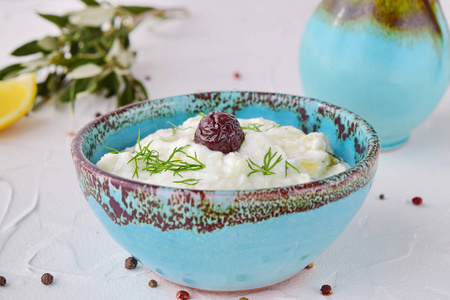希腊传统酱酸奶汁与黄瓜 大蒜 酸奶 橄榄油和柠檬在白色背景上的传统彩色碗。健康饮食的概念。地中海的生活方式