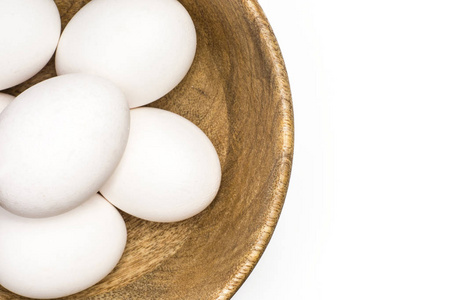 白色鸡蛋在木碗顶部视图被隔绝在白色背景