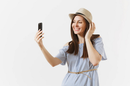 年轻漂亮的女子身着蓝色连衣裙, 帽子做自拍拍摄的手机或视频电话隔离在白色背景。人, 真诚的情感, 生活方式的概念。广告领域。复制