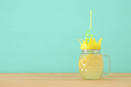 在木桌上用扭曲稻草的可爱菠萝形玻璃新鲜柠檬汁饮料的图像