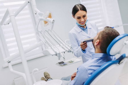 现代牙科诊所微笑牙医与患者选择牙种植体的肖像