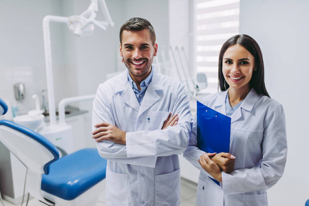 现代牙科诊所中两位微笑的医生的肖像看着相机站在工作场所