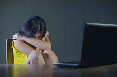 恐怖和强调的戏剧性的肖像亚洲韩国青少年女孩或年轻女子与笔记本电脑遭受网络欺负跟踪和骚扰互联网社会媒体密码黑客入侵