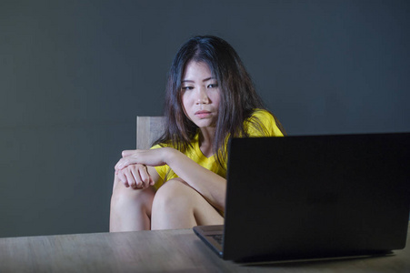 恐怖和强调的戏剧性的肖像亚洲韩国青少年女孩或年轻女子与笔记本电脑遭受网络欺负跟踪和骚扰互联网社会媒体密码黑客入侵