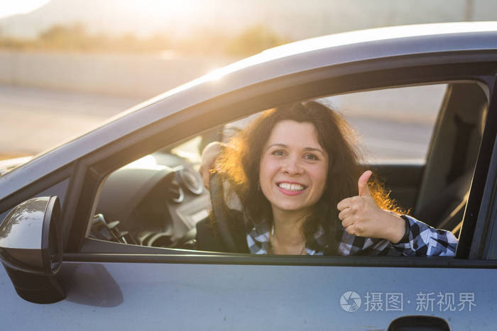 幸福的女人现身拇指和驾驶一辆新车