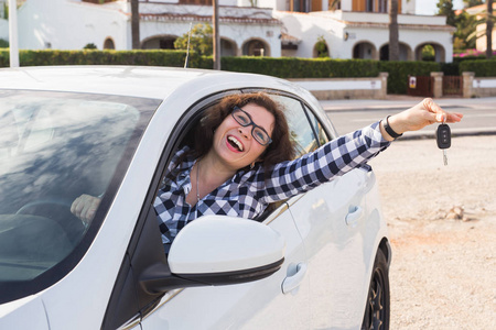 幸福的女人坐在车里手握钥匙从供货商在车展或沙龙