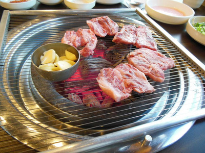 韩式烧烤桌上的红肉特写被烤在木炭上