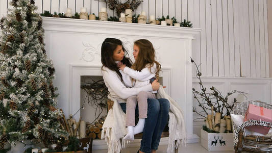 年轻的母亲和她的女儿，让自己轻松自在在壁炉旁的椅子上