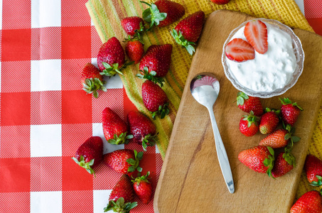 白色酸奶在小玻璃碗与切开草莓在顶部, 茶勺子在边, 在木板材切开板
