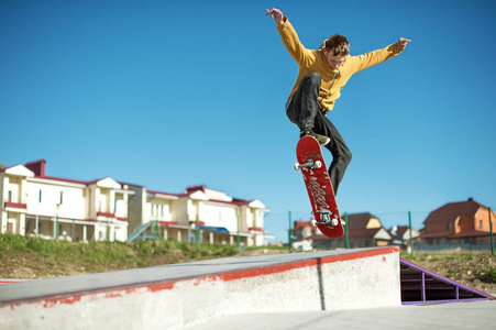 一个少年滑板并在滑板上城市的郊区奥利把戏