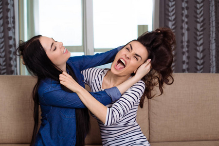 仇恨头发两个好斗的年轻女子打架, 互相抢夺头发照片