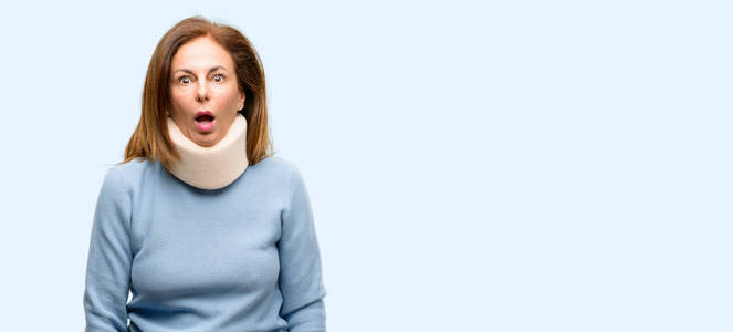 受伤的妇女戴着颈撑项圈吓坏了, 表示恐慌和恐惧孤立的蓝色背景