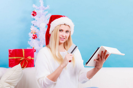 圣诞节的时间概念。年轻女子青少年女孩与 tablet pc 笔记本电脑和信用卡在沙发上在首页做在线购物，买礼物，浏览乐趣