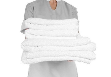 白色背景的干净毛巾堆的年轻女服务员