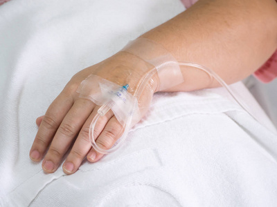 输液女人病人在输液中接受盐水溶液, 在医院的一个女人的手关闭盐水