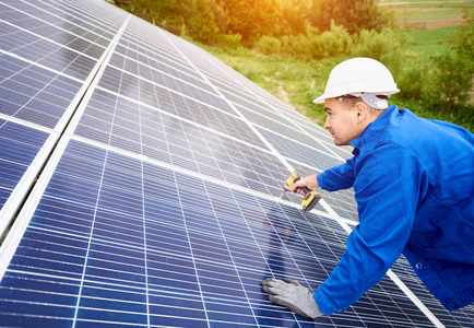 建筑工人用螺丝刀将光电面板与太阳能系统连接起来。太阳能系统专业安装与建设替代能源与金融投资理念