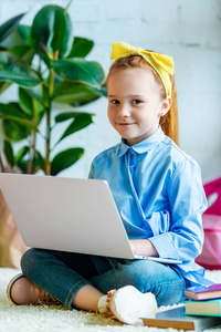可爱的小孩子使用笔记本电脑和微笑在相机