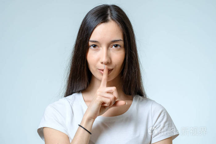 保持沉默美丽的年轻女子拿手指在唇上