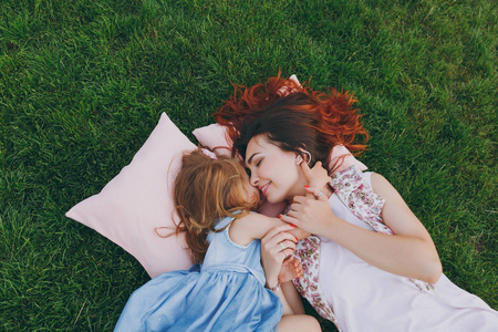 温柔的女人和可爱的小女孩躺在草地上的枕头上拥抱, 拥抱和休息, 玩得开心。妈妈小女儿母亲节, 爱家庭, 亲子, 童年概念