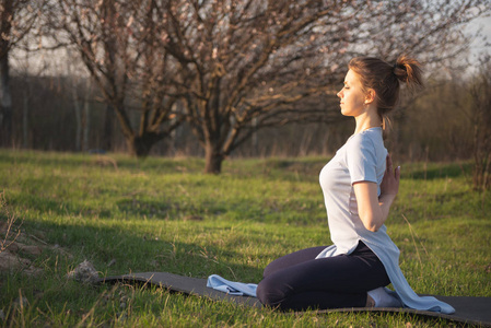 瑜伽。在露天冥想。春季日落和一个练习瑜伽的女人