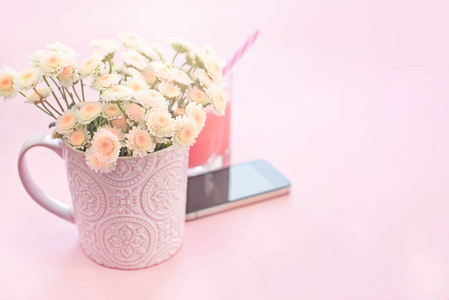 一束菊花花在一杯茶玻璃鸡尾酒电话里。节日粉红色背景
