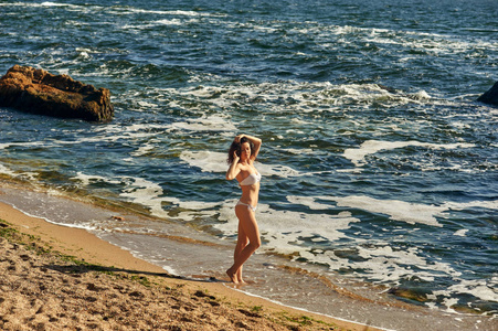 一个年轻的女人在沙滩上沐浴清晨的阳光