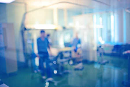 男工人在蓝色制服旁边的病人床在急诊室, 未聚焦的背景