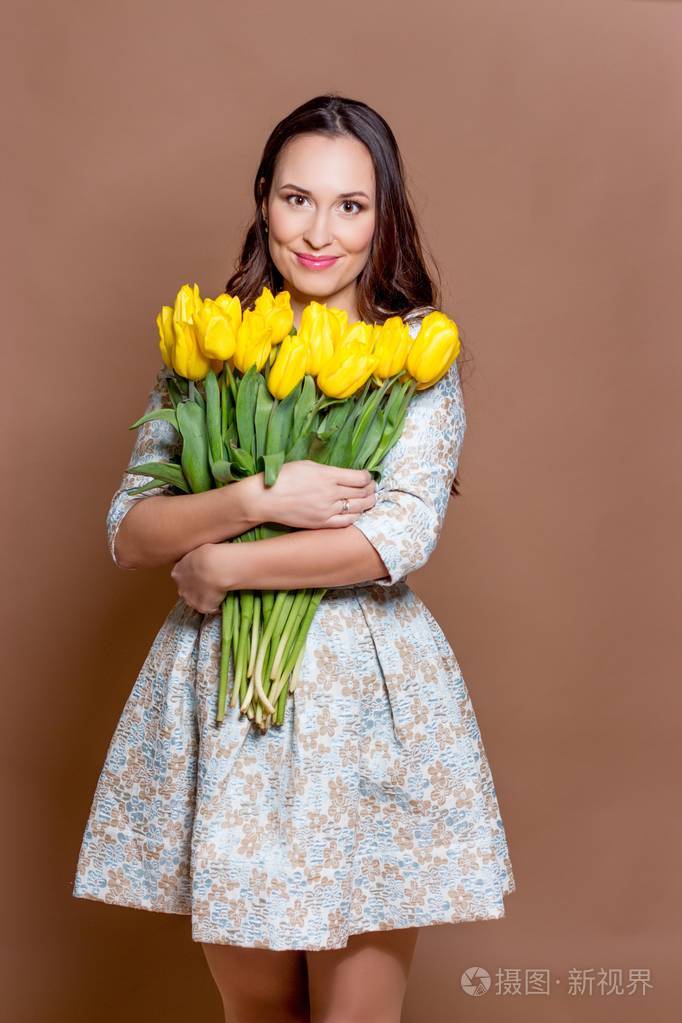 照片 年轻漂亮的女人抱着一束黄色郁金香.春天.jpg