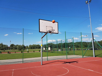 篮球圈球在阳光明媚的日子里飞进篮球圈.篮球场在露天与人造表面.