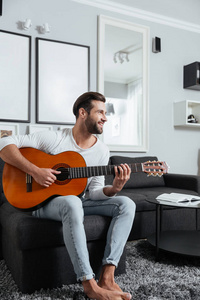 快乐的人坐在沙发上玩吉他